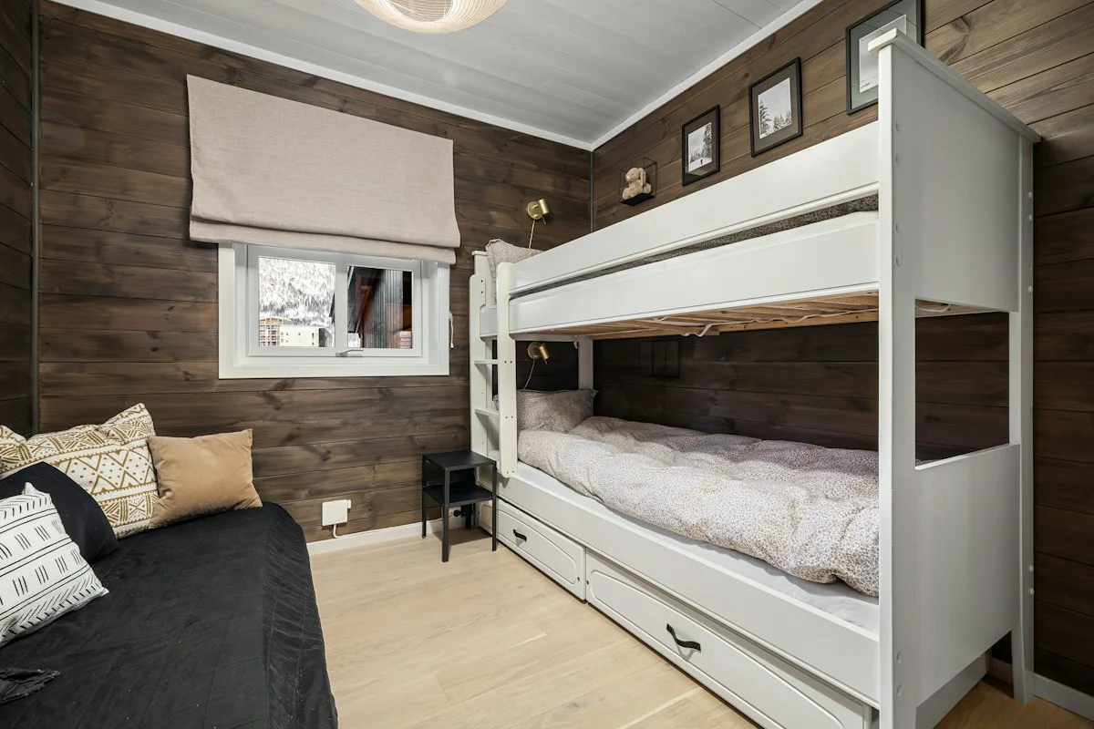 White bunk beds and a daybed in a timber-lined room