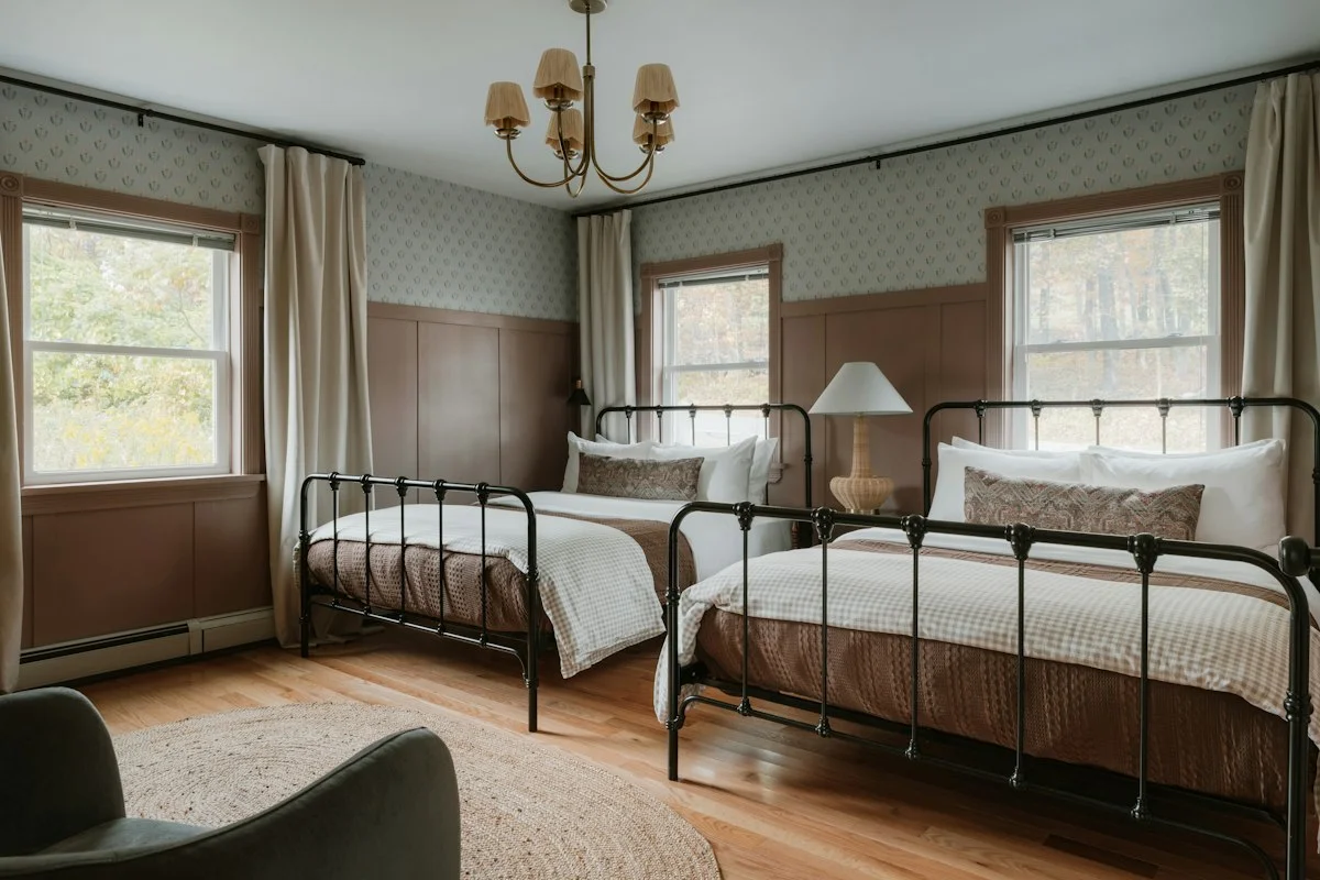 Two iron-framed single beds in a panelled room